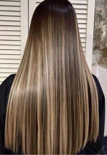 Cabello largo y liso con mechas rubias sobre una base oscura visto desde atrás.