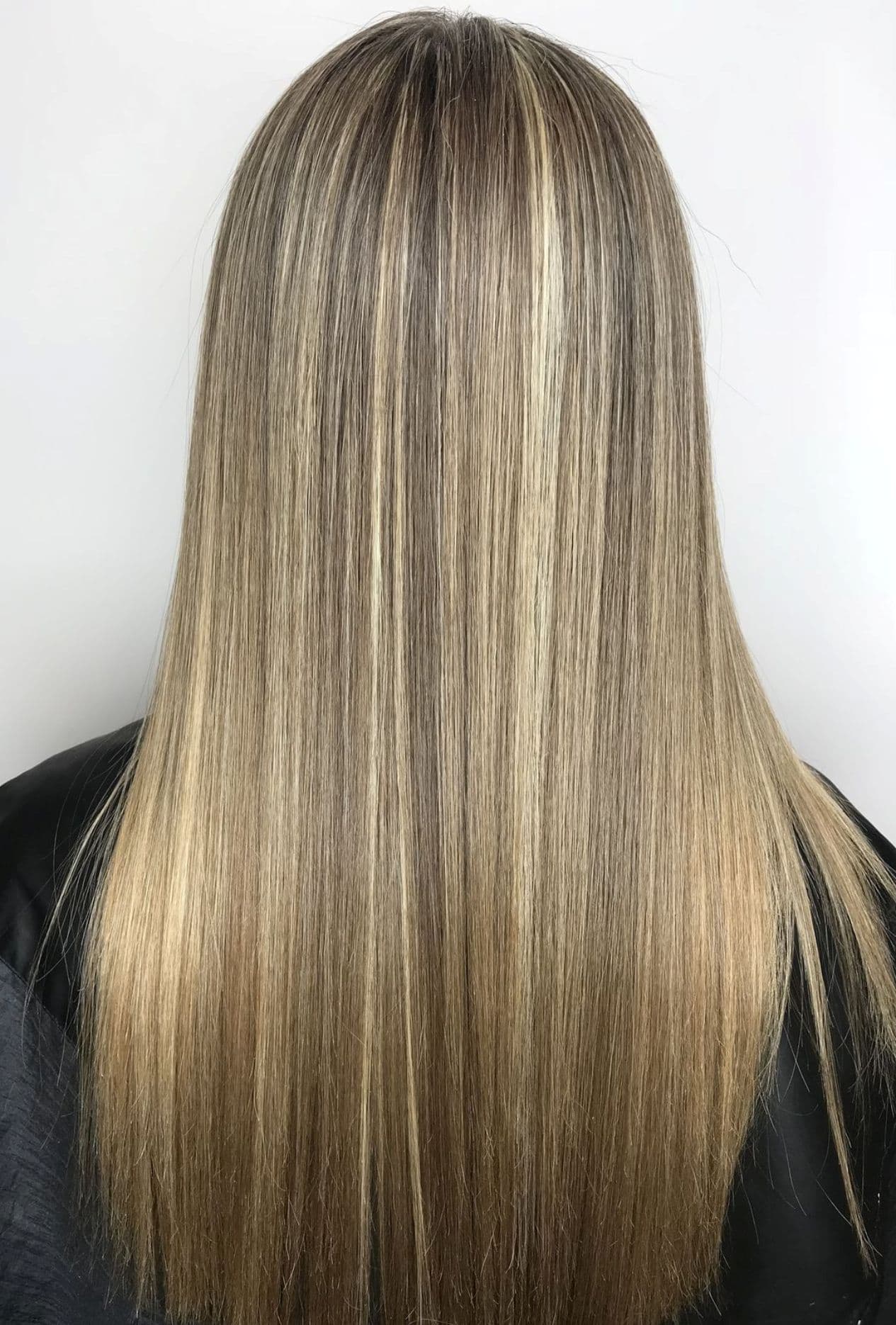 Cabello largo y liso con reflejos rubios sobre base castaña, visto desde atrás.