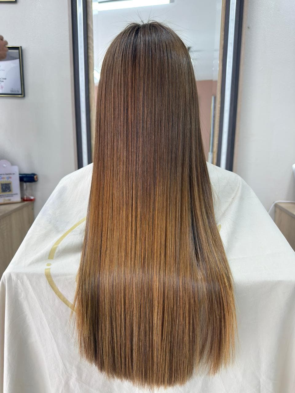 Cabello largo y liso de color castaño con reflejos dorados y acabado brillante y sedoso.