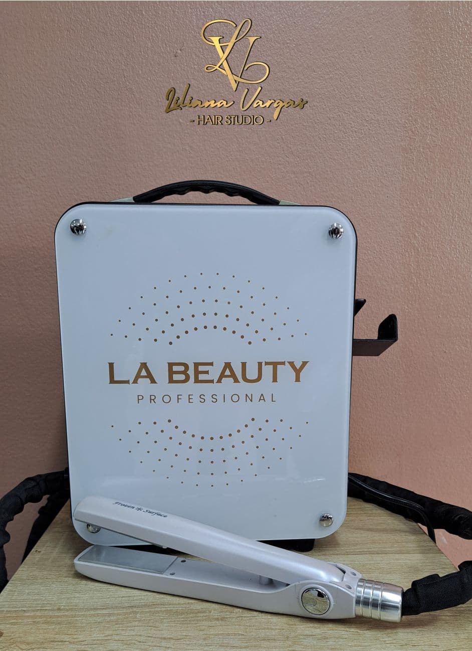 Máquina blanca LA BEAUTY PROFESSIONAL y plancha de pelo sobre una mesa de madera clara.